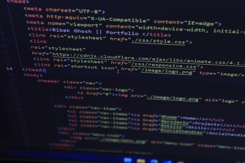 A photograph of a computer screen displaying lines of code in a text editor, with syntax highlighting in various colors including yellow, red, and blue. The code appears to be HTML or a similar langua